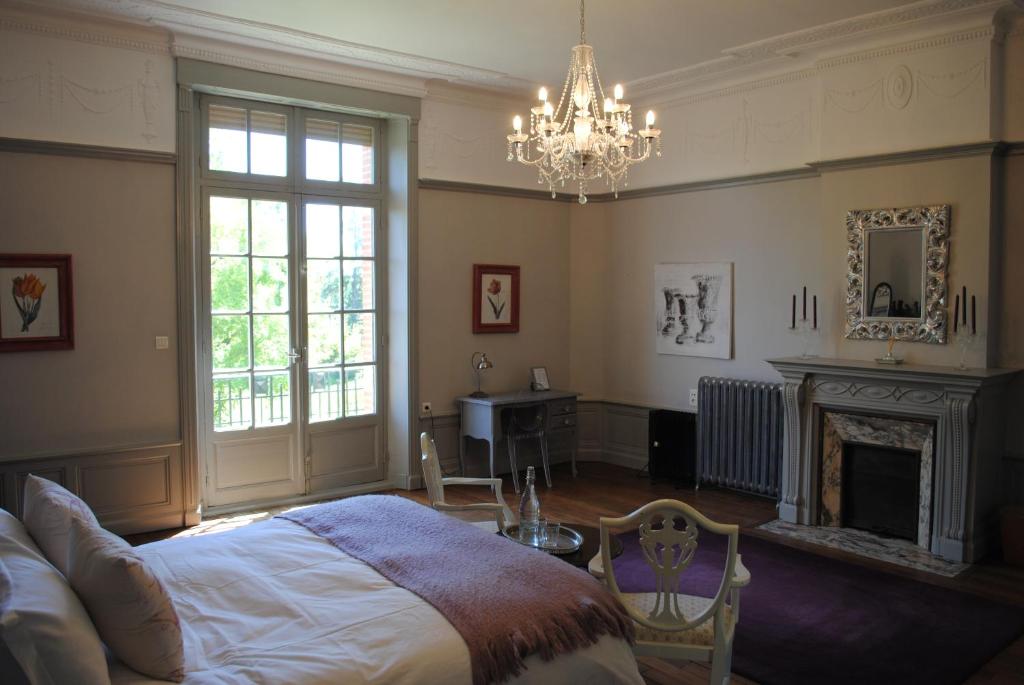 una camera con letto, camino e lampadario a braccio di Chateau Mezger ad Albefeuille-Lagarde