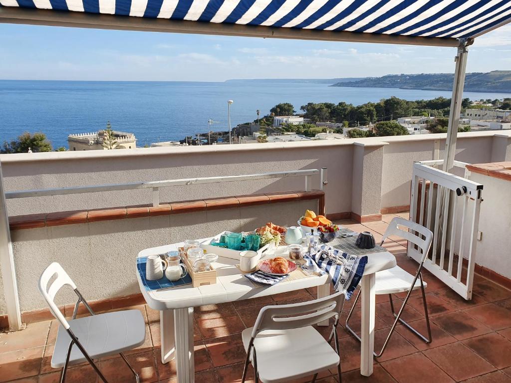 un tavolo e sedie su un balcone con vista sull'oceano di Casa con terrazza vista 180° sulla costa orientale a Santa Cesarea Terme