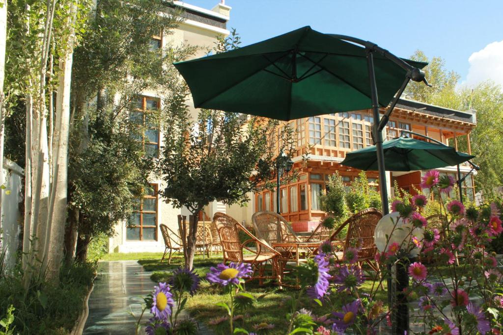 a patio with chairs and an umbrella and flowers at Hotel Ladakh Greens in Leh