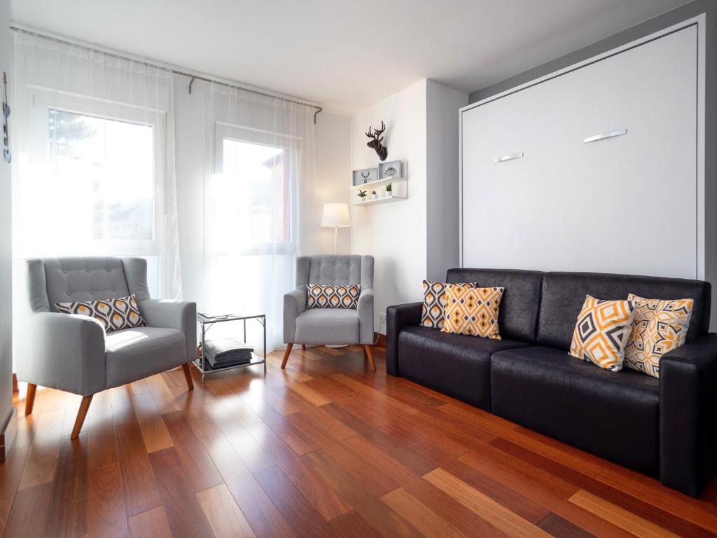 sala de estar con sofá negro y silla en Apartamento Monte Perdido, en Boltaña