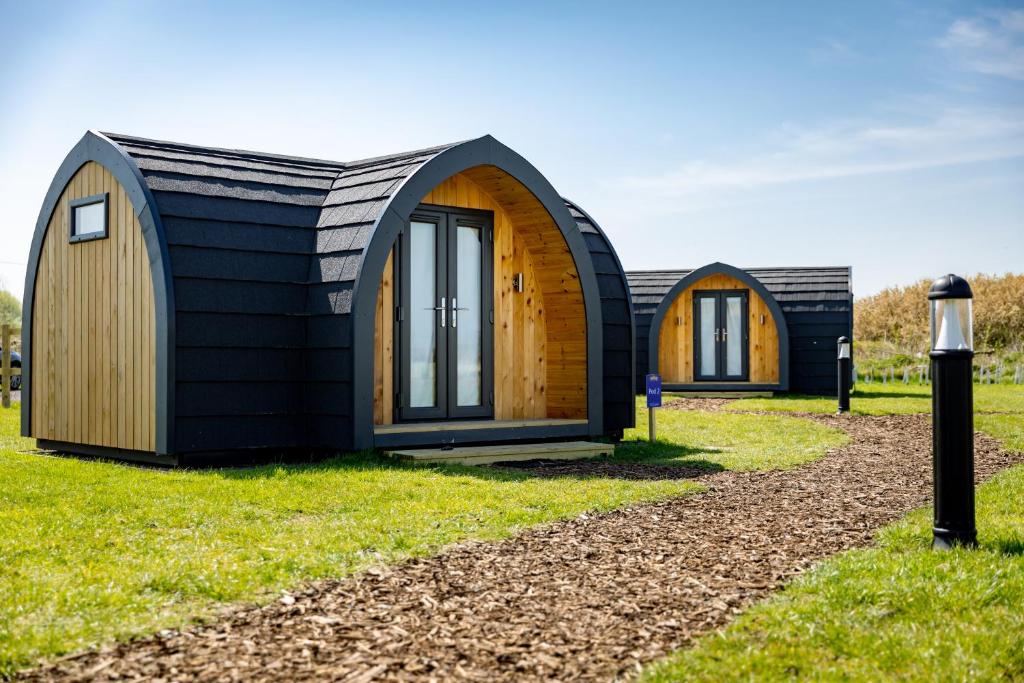 two small cottages in a field with grass at Camping Pods, Golden Sands Holiday Park in Dawlish