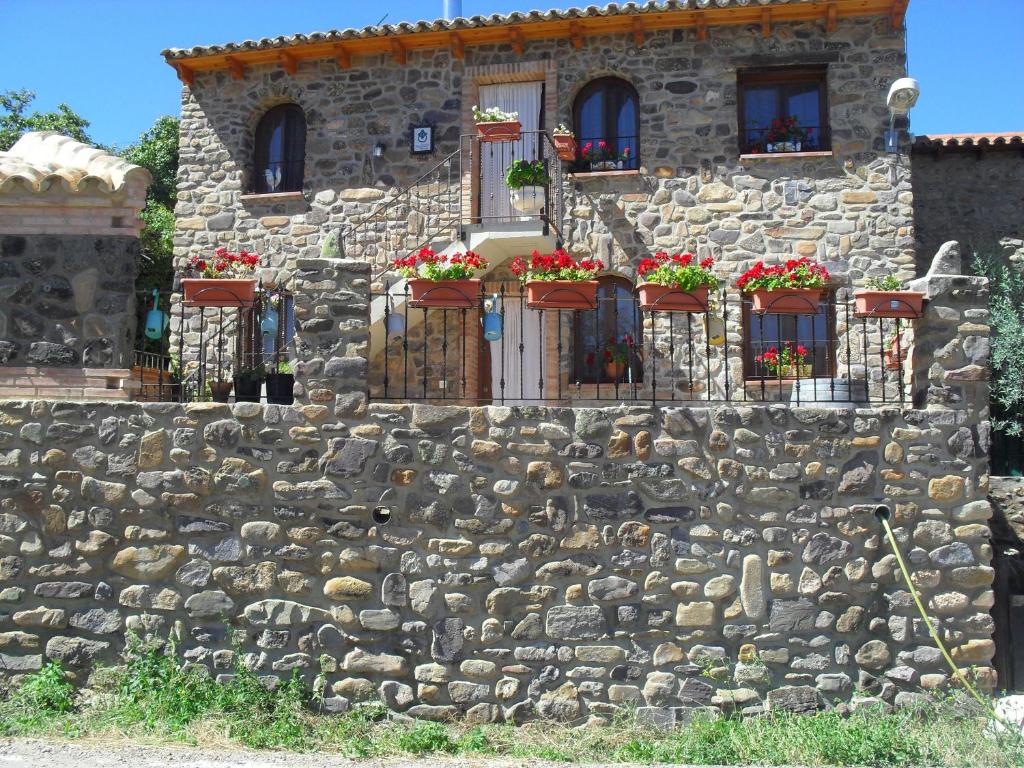 una casa de piedra con flores en una pared de piedra en El Corralico del Moncayo, en Alcalá de Moncayo