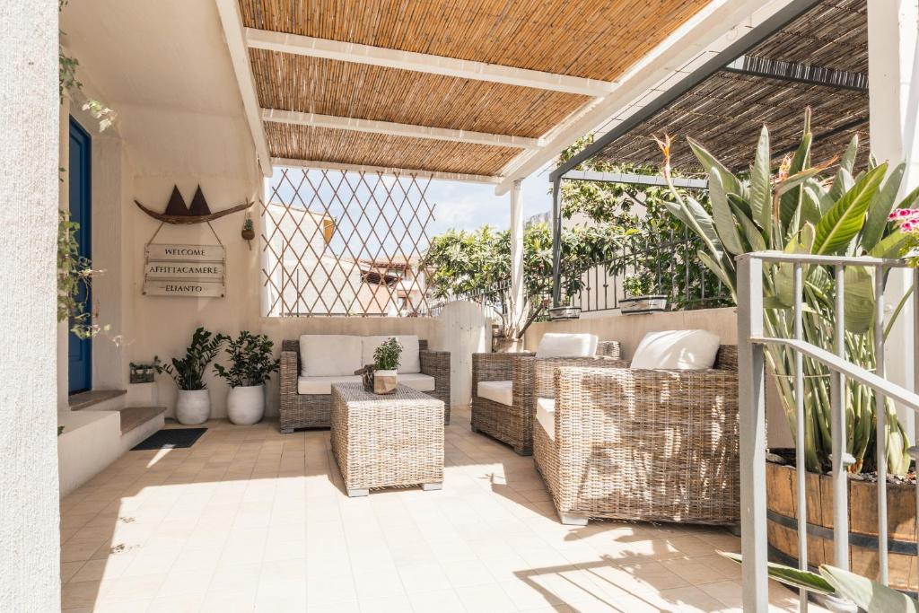 an outdoor patio with wicker furniture and plants at B&B Elianto in Santa Maria Navarrese