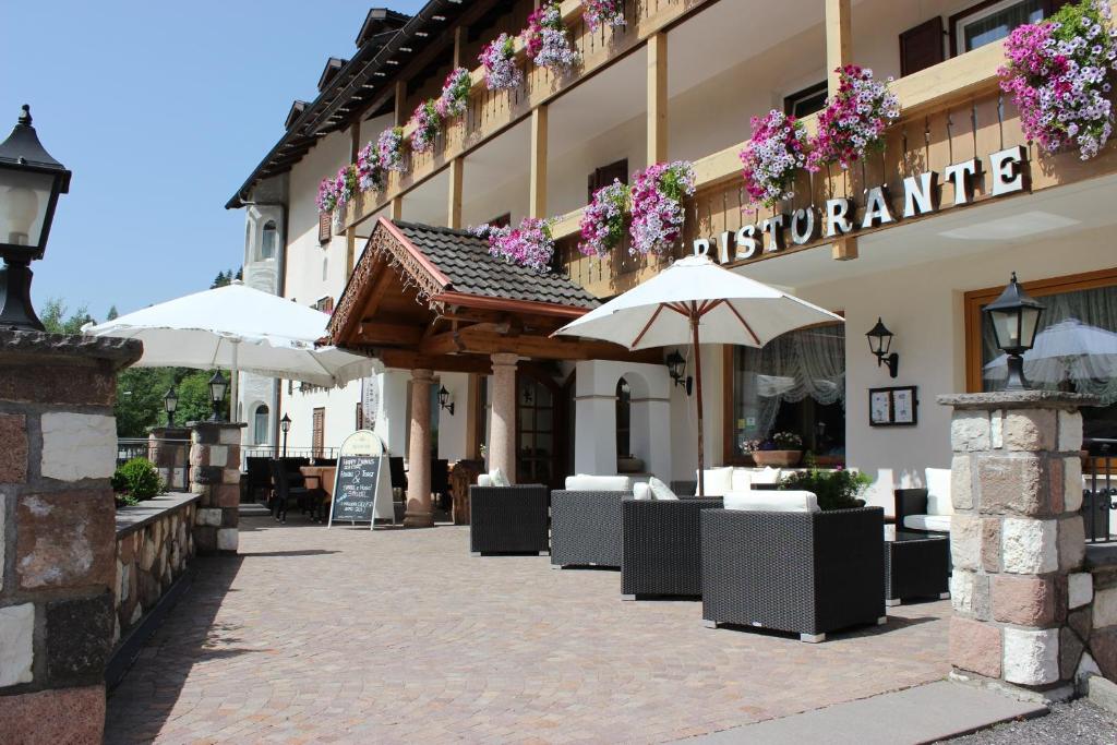un ristorante con tavoli e ombrelloni di fronte a un edificio di Hotel Rosalpina a Soraga
