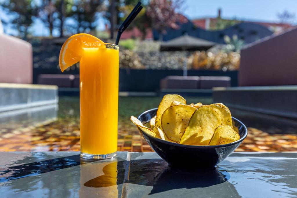 a bowl of chips and a glass of orange juice at Evidencia Belverde Hotel in Amora