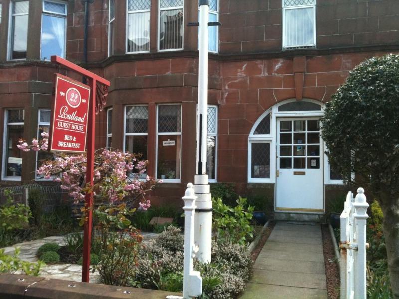 a red brick house with a sign in front of it at Rutland House in Largs