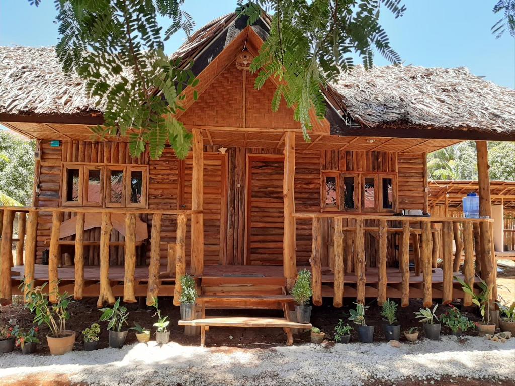 a wooden cabin with a porch and a thatched roof at Travis Post Homestay in Siquijor