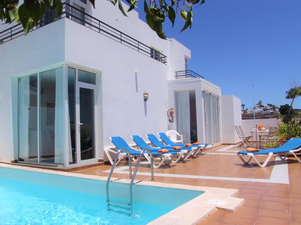 プエルト・デル・カルメンにあるCasas Luis with private poolのスイミングプール、青い椅子が備わるヴィラです。