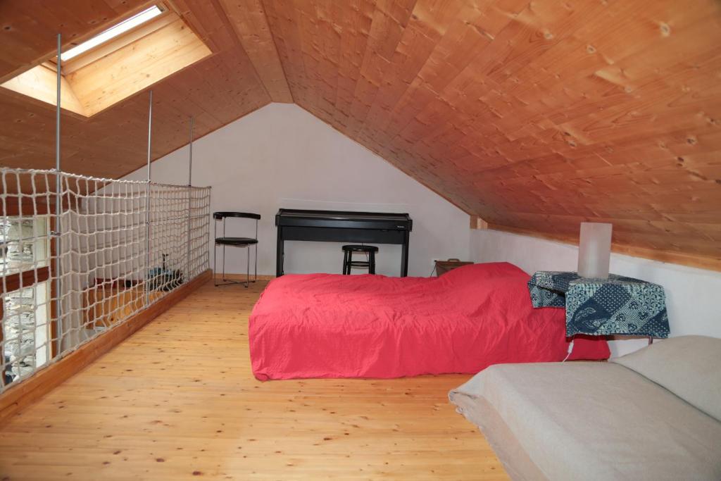 1 dormitorio con cama roja y chimenea en Rustico, en Verdabbio