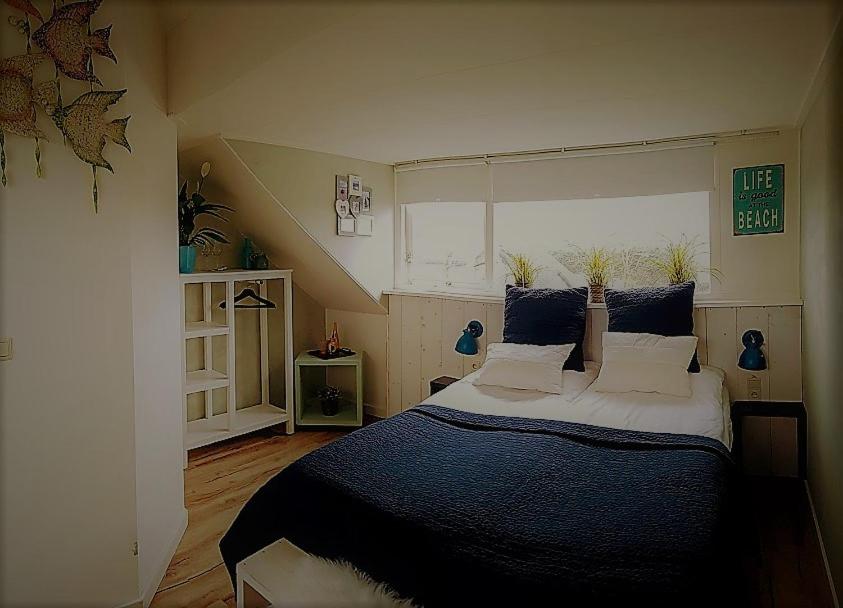 een slaapkamer met een groot bed met blauwe lakens en kussens bij B&B Duinroos De Koog - Texel in De Koog
