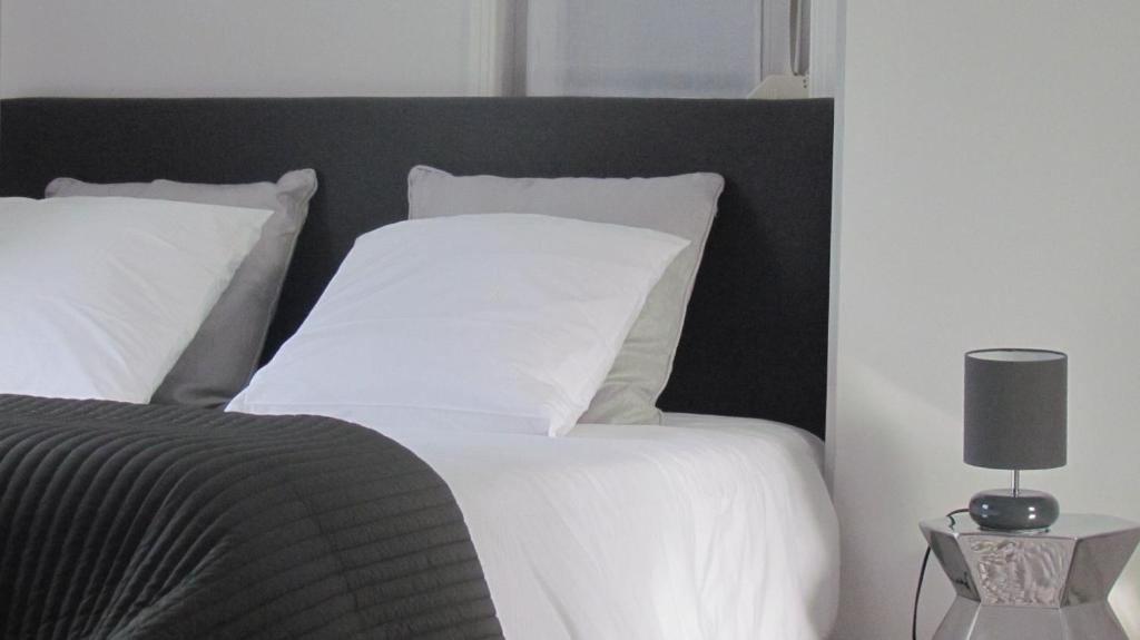 Bett mit weißer Bettwäsche und einem schwarzen Kopfteil in der Unterkunft Gite Histoire de Maison in Arras