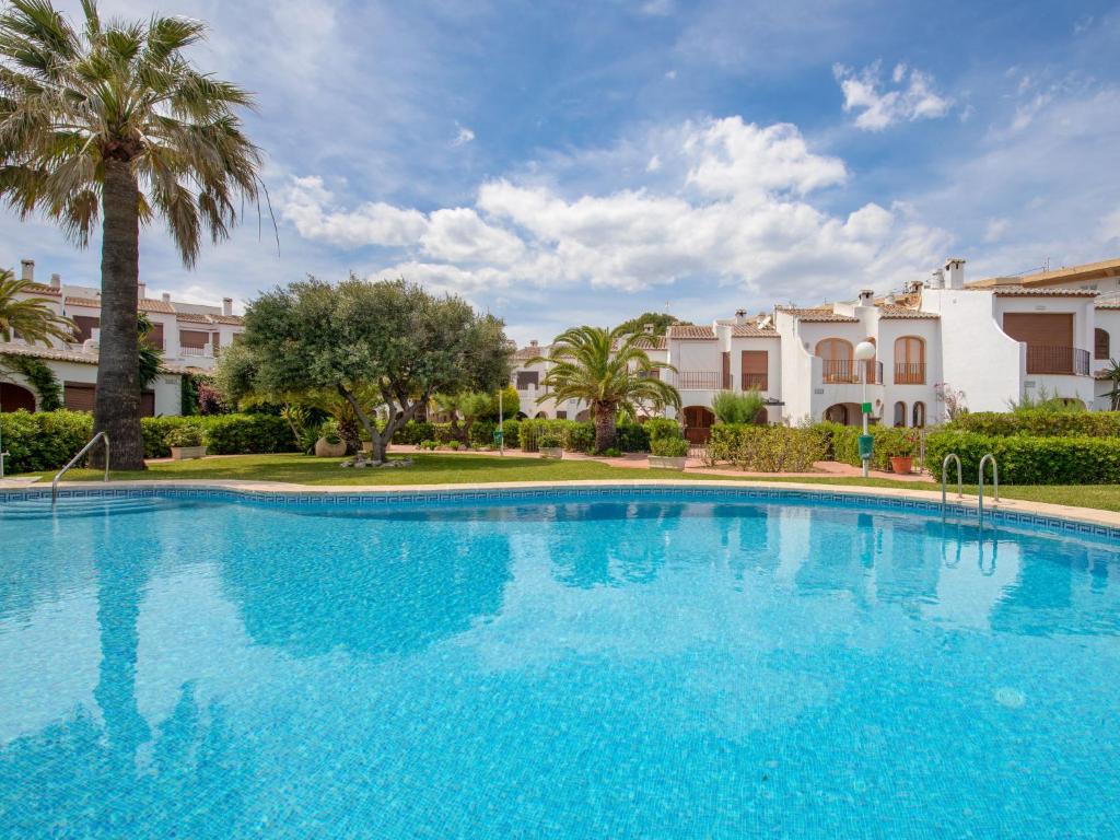 Una gran piscina azul con palmeras y edificios. en Holiday Home Montanar Plus-1 by Interhome, en Jávea