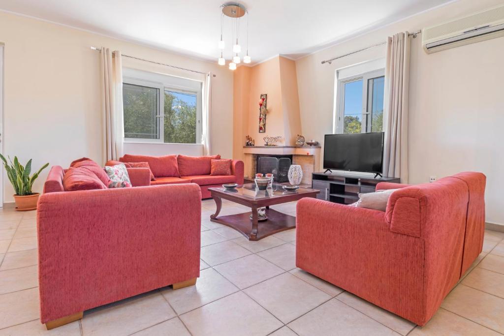 ein Wohnzimmer mit roten Sofas und einem TV in der Unterkunft Lina's Amazing House in Ialysos in Ixia