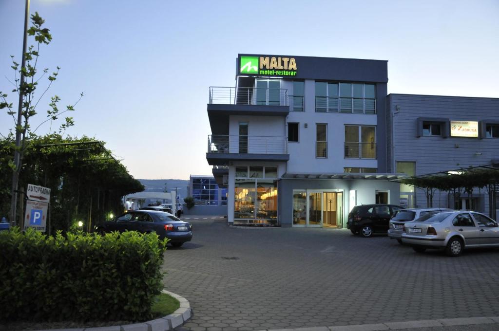 un parking avec des voitures garées devant un bâtiment dans l'établissement Hotel Malta, à Mostar
