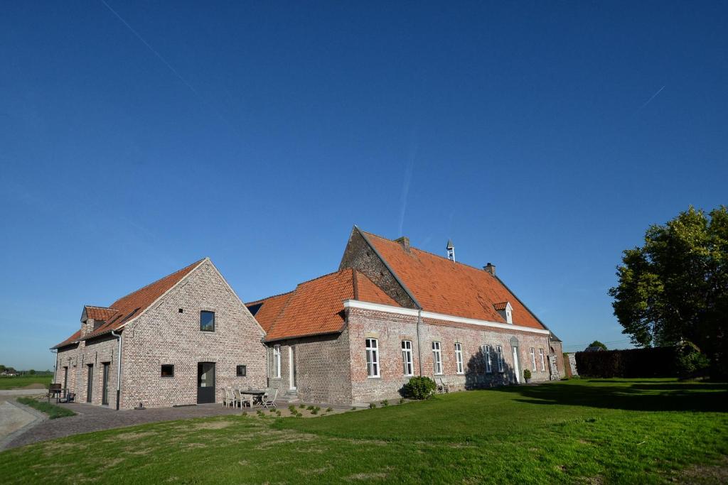 un gran edificio de ladrillo con techo rojo en Hoeve Ten Rooden Duifhuize en Sint-Denijs