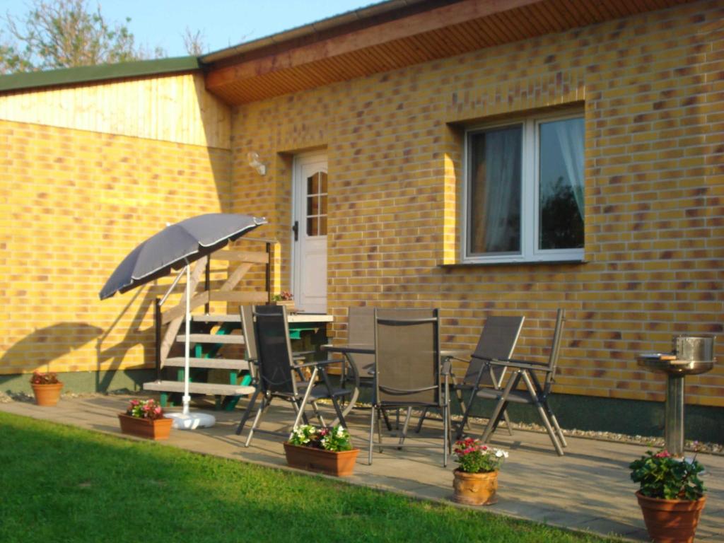 une terrasse avec une table, des chaises et un parasol dans l'établissement Ruegen_Fewo 37, à Zirkow