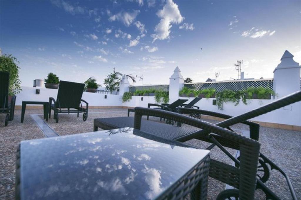 - une terrasse avec une table et des chaises dans un bâtiment dans l'établissement Ferreira Hostal Boutique, à Conil de la Frontera