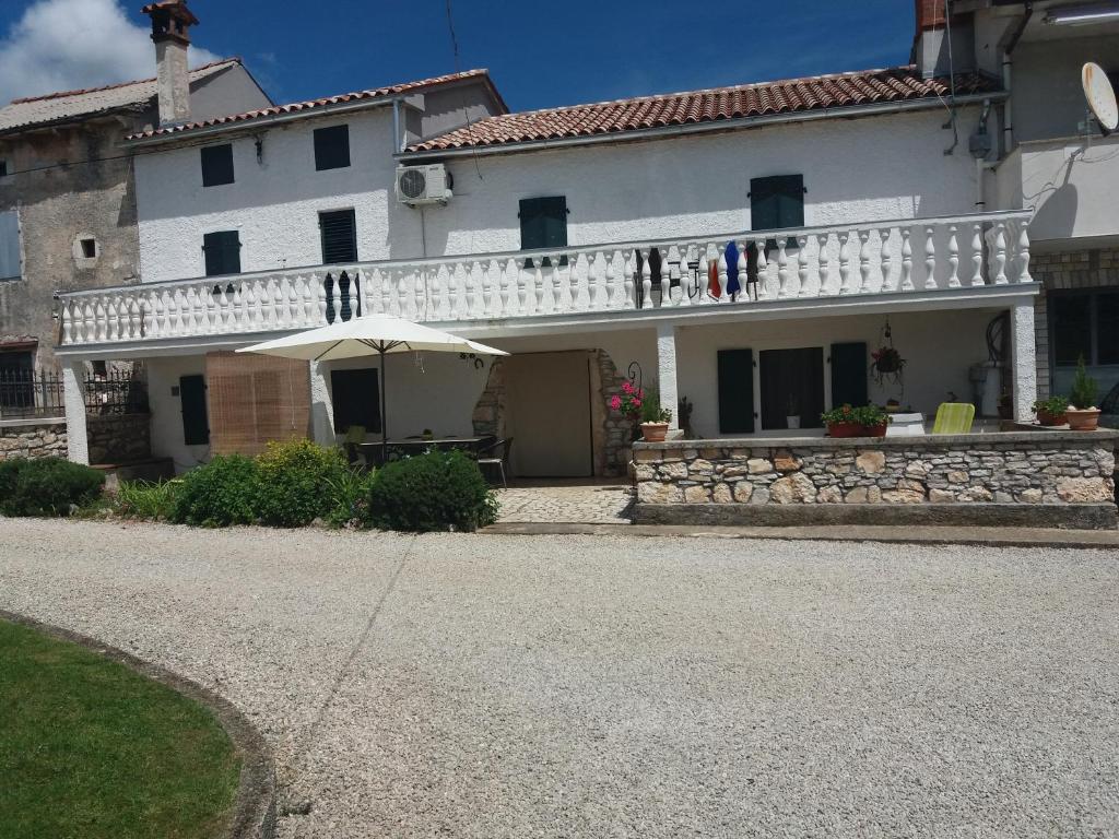 a white house with a balcony with an umbrella at Casa Irma in Žminj