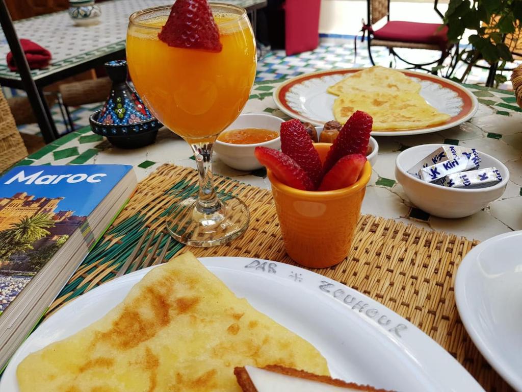 a table with plates of food and a glass of orange juice at Riad Dar Zouhour in Rabat