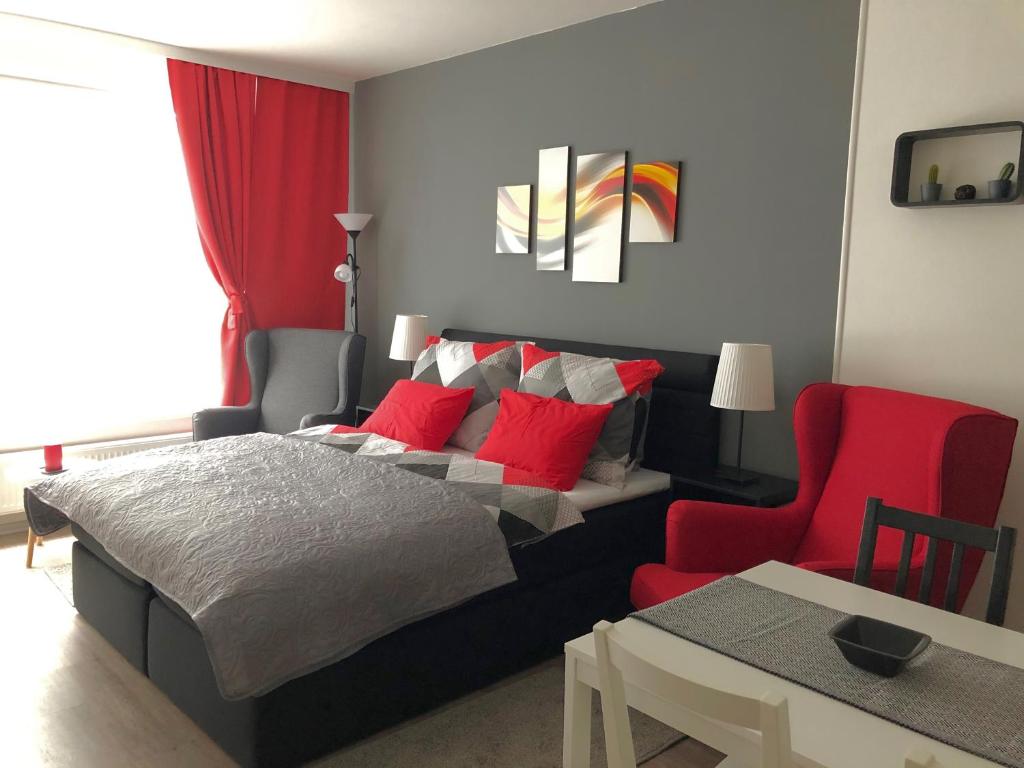 a bedroom with a bed and a red chair at RS Apartments in Olomouc