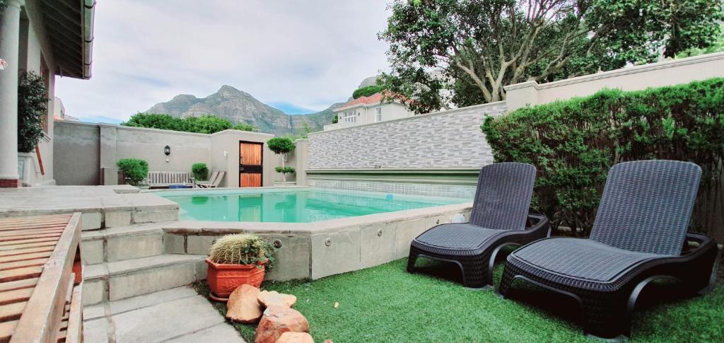 un patio trasero con piscina y 2 sillas en Redbourne Hilldrop Guesthouse B&B en Ciudad del Cabo