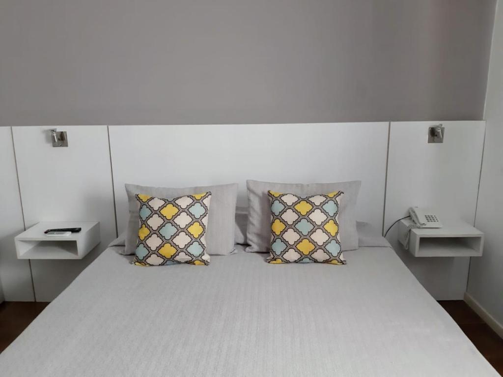 a bedroom with a white bed with pillows at Hotel Tunuyan in Tunuyán