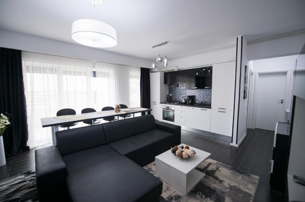 een woonkamer met een zwarte bank en een tafel bij Apartel Black & White in Mamaia Nord – Năvodari