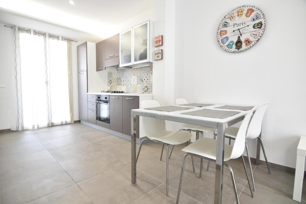 a kitchen with a table and chairs and a clock on the wall at The three diamonds of Marina di Ragusa in Marina di Ragusa