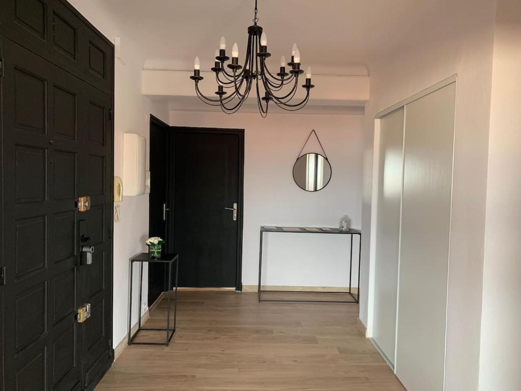 a hallway with a black door and a chandelier at BEAU T4 100M2 PALAIS DES ROIS DE MAJORQUE in Perpignan