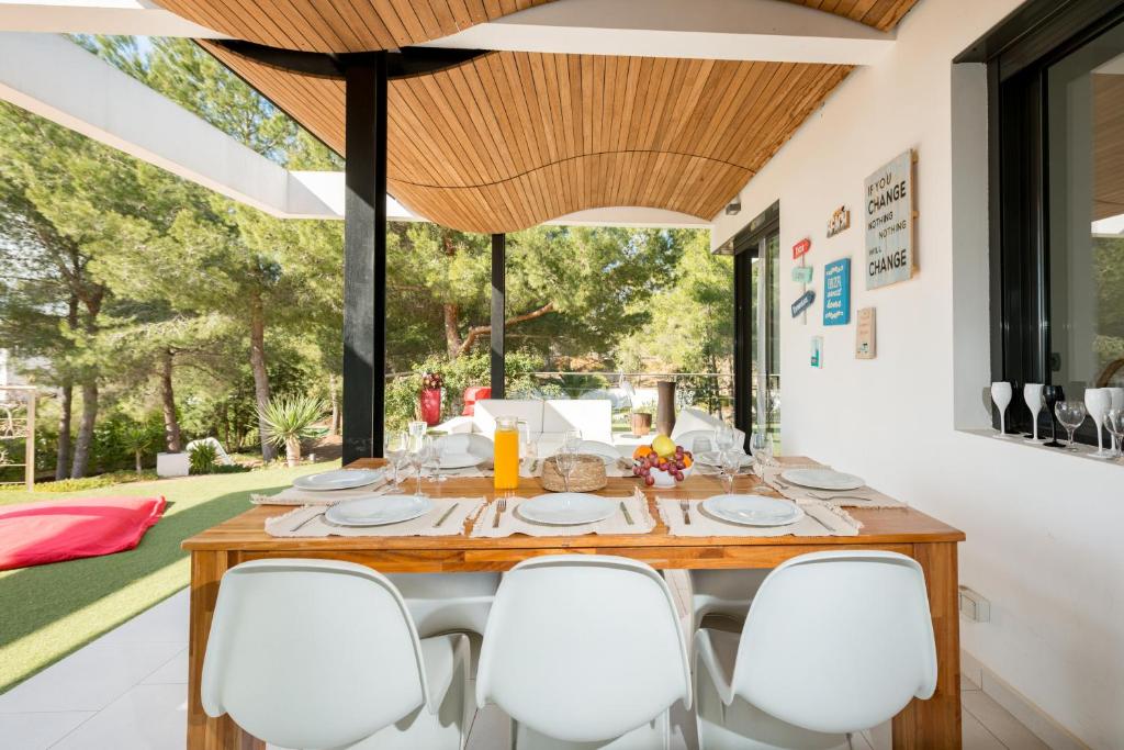 a dining room with a wooden table and white chairs at Nyumba ya Sun in Cala Tarida