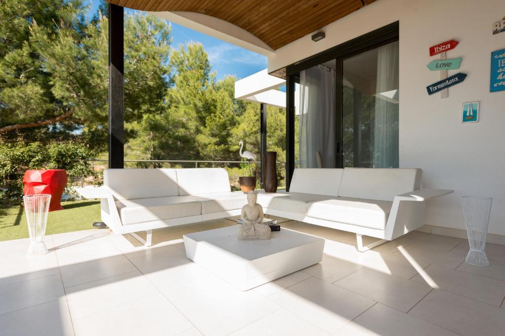 a living room with white furniture and large windows at Nyumba ya Sun in Cala Tarida