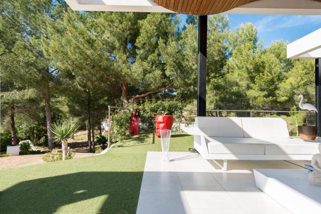 a patio with a white couch and a red chair at Nyumba ya Sun in Cala Tarida