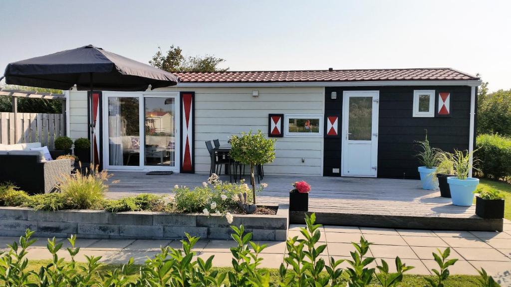 a small house with a patio and an umbrella at Olmenduin Chalet Olm Zeeland in Serooskerke