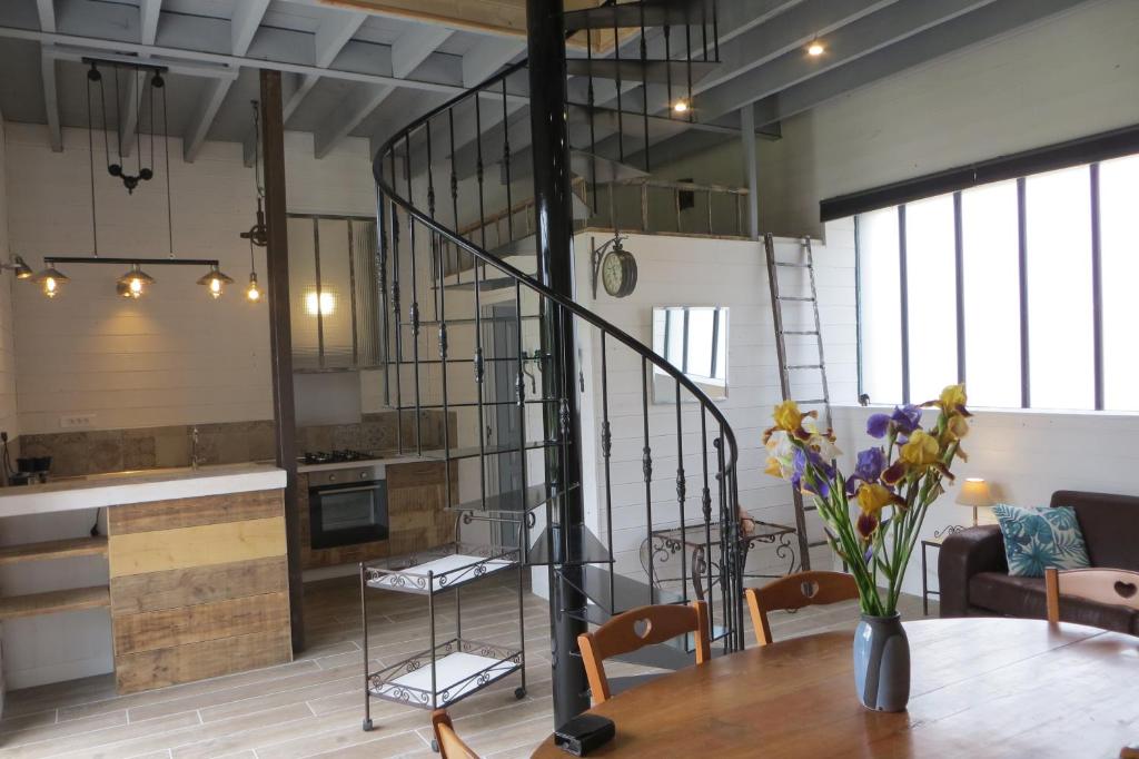 a kitchen and a dining room with a spiral staircase at LA GRANGE in Montlouis-sur-Loire
