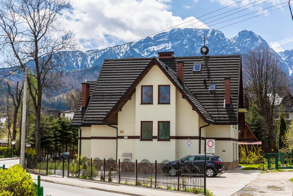 a house with a fence in front of a mountain at TatryTop Apartamenty Zaciszne in Zakopane