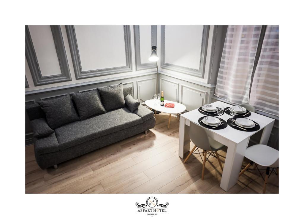 una sala de estar con un sofá y una mesa en L'Impérial Appart Hotel Poitiers, en Poitiers