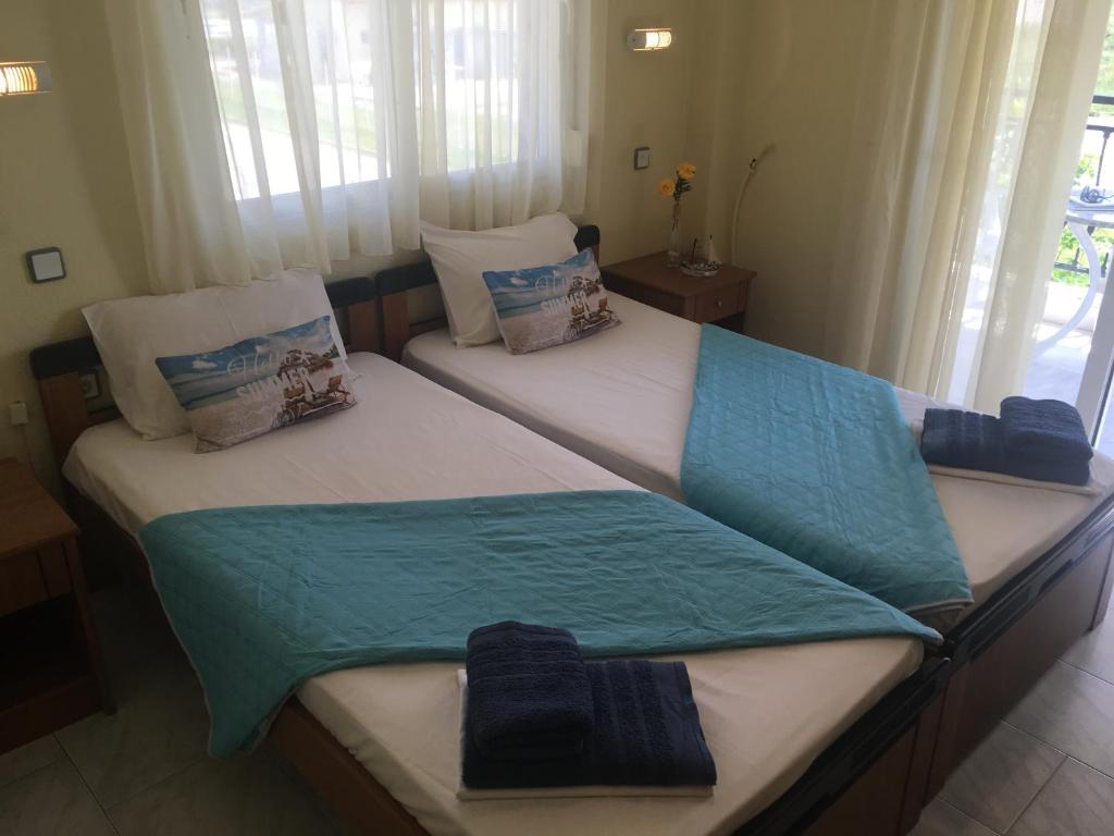two twin beds in a room with windows at Dionisos Blue in Paralia Dionysiou