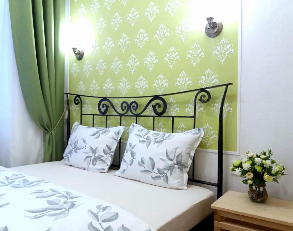 a bed with white pillows and a green wall at Guest House Izola in Izola