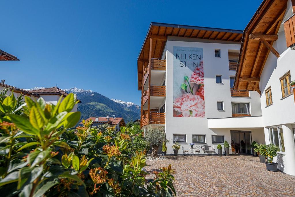a view of the exterior of a hotel with mountains in the background at Residence Apartment Nelkenstein in Schenna