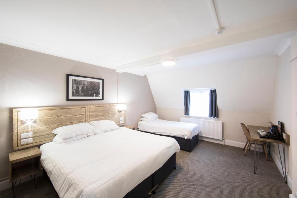 a hotel room with two beds and a window at Half Moon, Sherborne by Marston's Inns in Sherborne