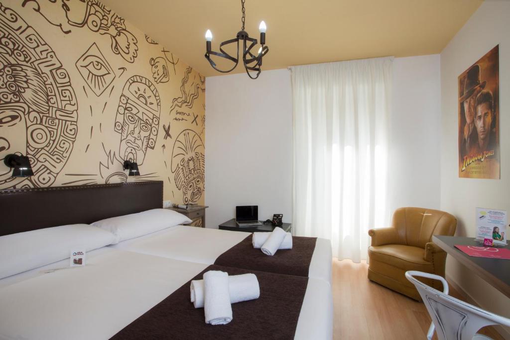 um quarto de hotel com uma cama e uma cadeira em Casual del Cine Valencia em Valência
