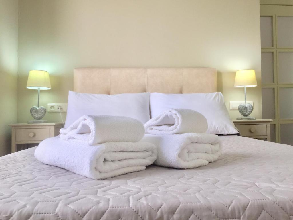 Una cama con mantas blancas y almohadas. en Caesarina, en Cáceres