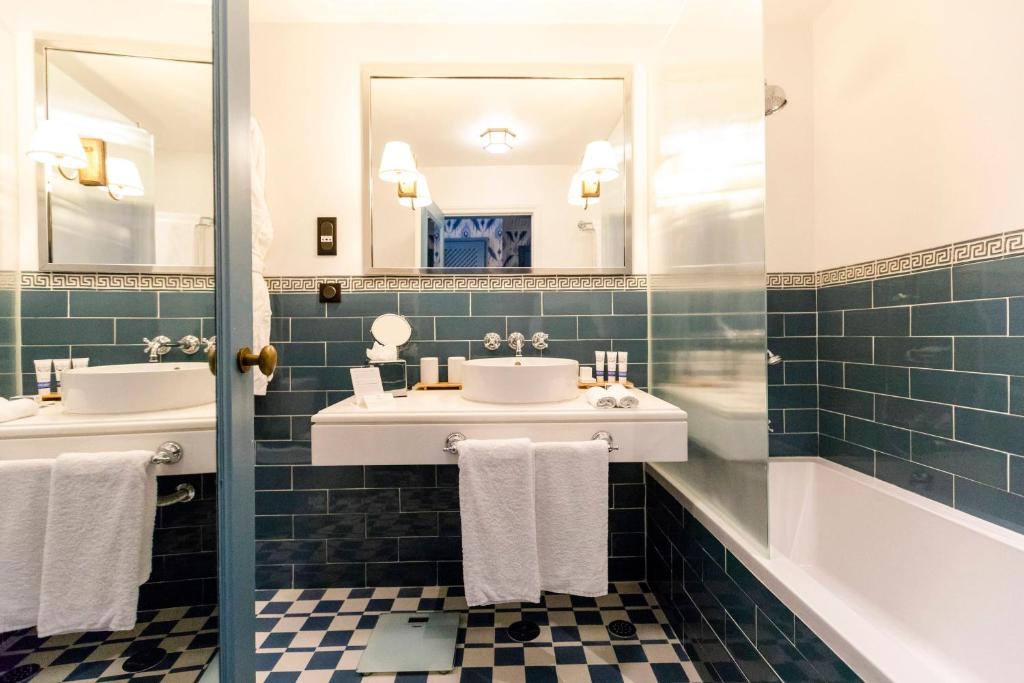 a bathroom with two sinks and a tub and mirrors at The Albatroz Hotel in Cascais
