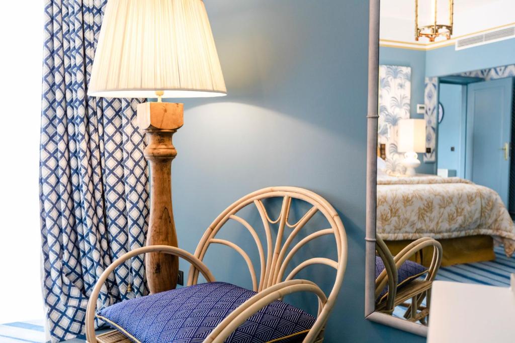 a room with a chair and a lamp and a mirror at The Albatroz Hotel in Cascais