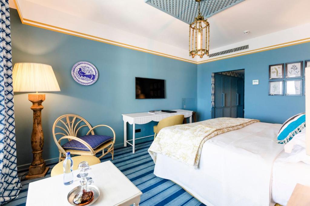 a bedroom with blue walls and a bed and a desk at The Albatroz Hotel in Cascais
