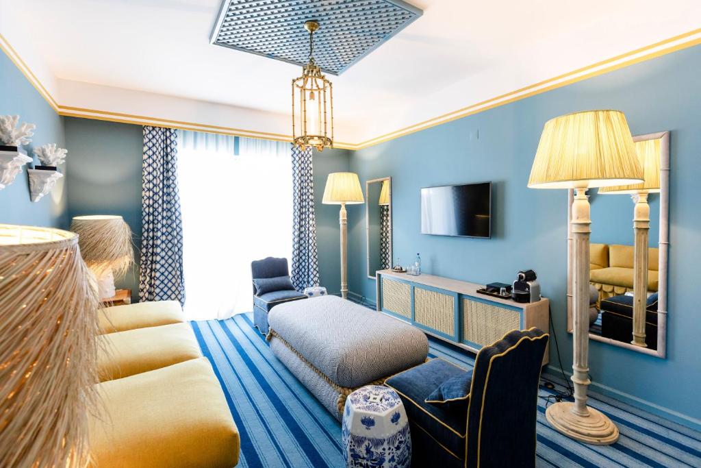 a hotel room with blue walls and a bed and a couch at The Albatroz Hotel in Cascais