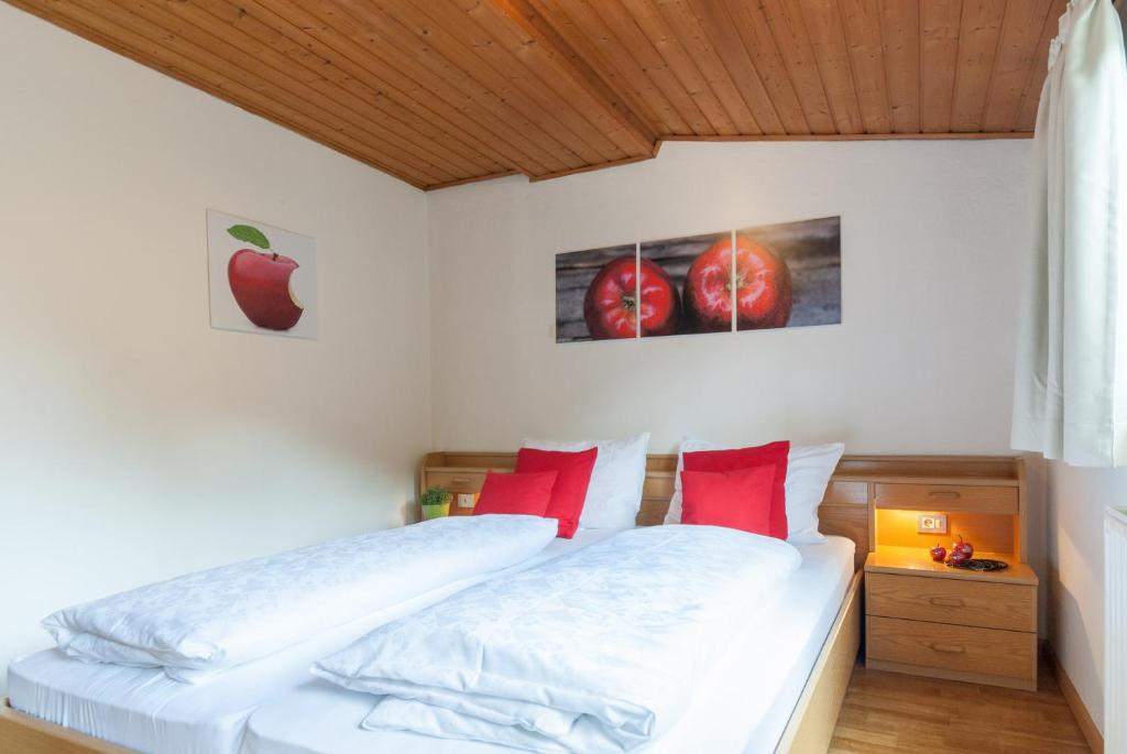 ein Schlafzimmer mit einem Bett mit roten Kissen und einem Apfelbild in der Unterkunft Gasthof Hanni in Meran