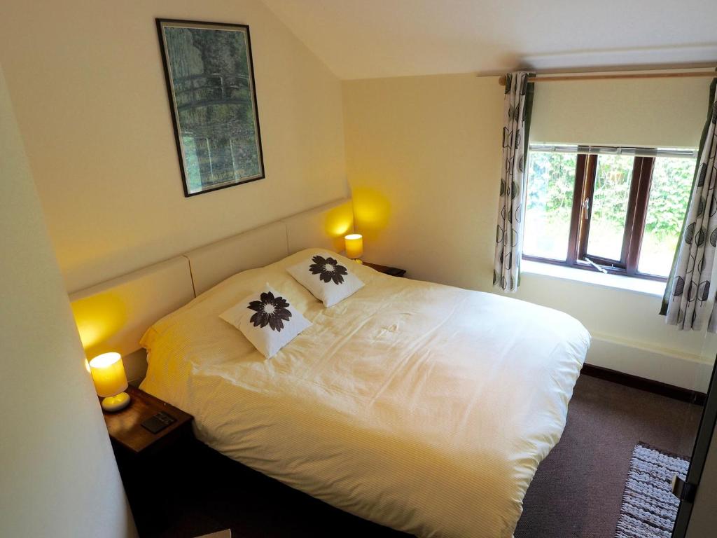 a bedroom with a white bed with two pillows on it at Swallow Cottage at Duffryn Mawr Cottages in Hensol