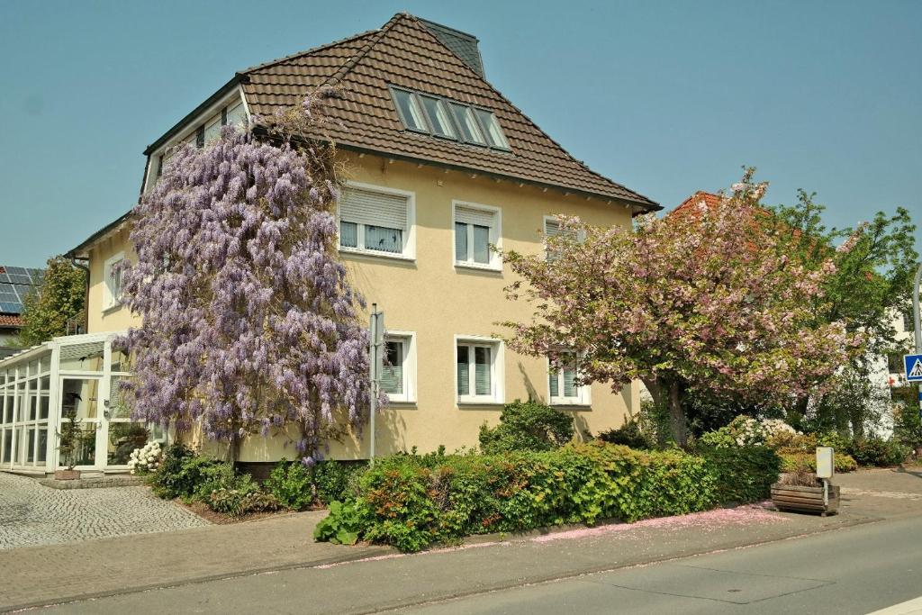 una casa con un árbol de flores púrpura delante de ella en Pension Franzbäcker en Warburg