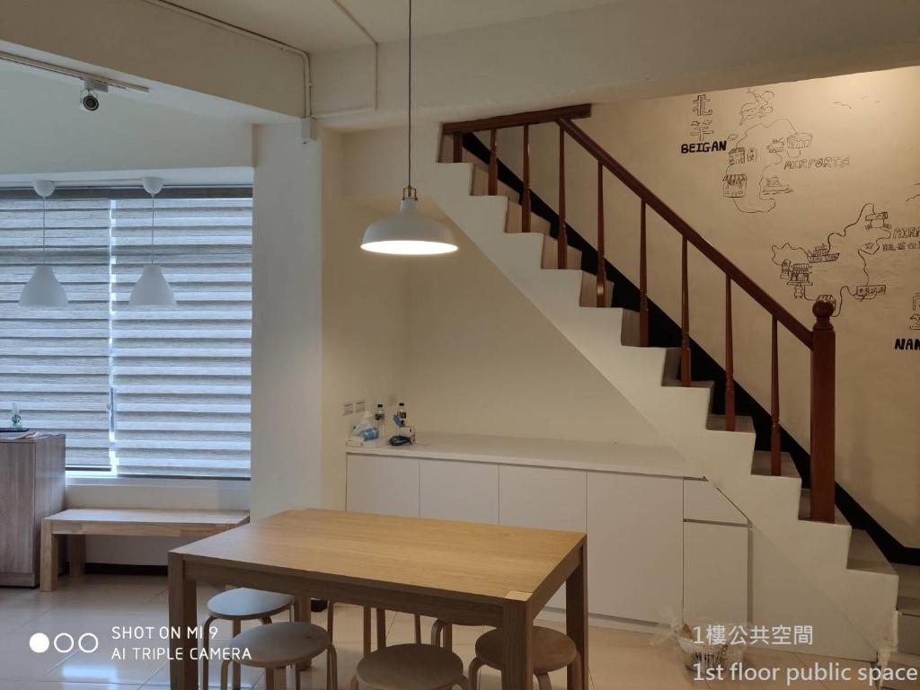 a dining room with a table and a staircase at Simple life hostel in Nangan